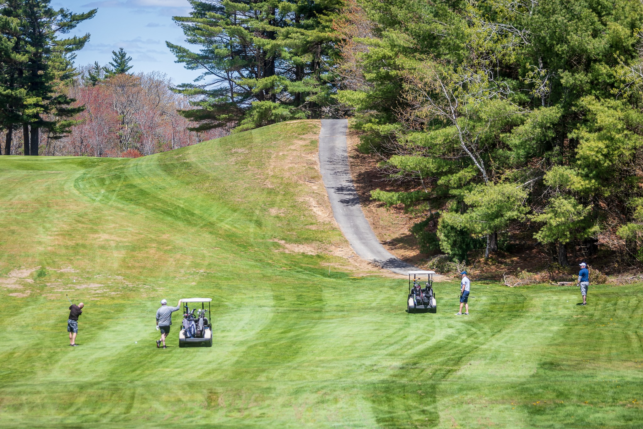 Golfers with carts on golf course fairway with cart path